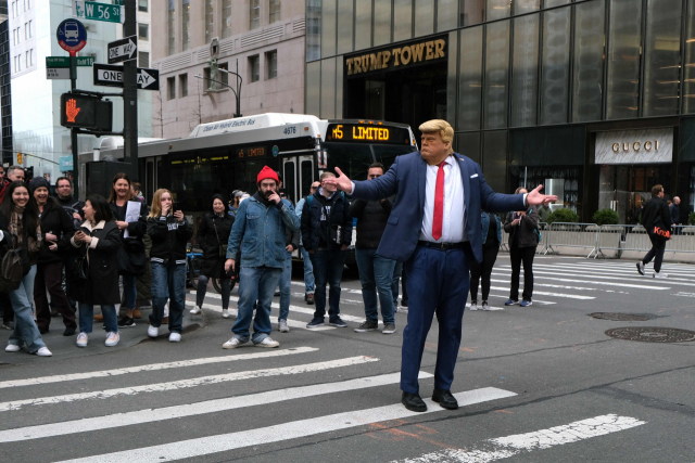 한 사람이 지난달 31일(현지시간) 미국 뉴욕 트럼프 타워 인근에서 도널드 트럼프 전 대통령의 얼굴을 본뜬 가면을 쓰고 거리를 걷고 있다. AFP연합뉴스