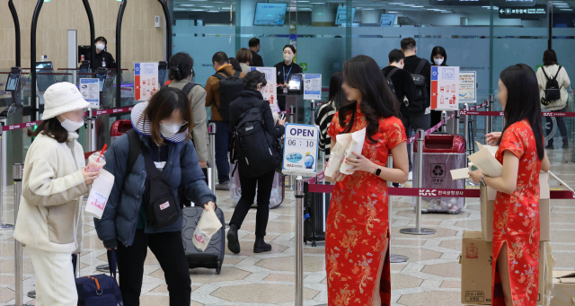 코로나19로 중단됐던 김포-북경·상해 노선 운항이 재개된 가운데 3월 27일 오후 한국공항공사 관계자들이 김포공항에서 김포-북경·상해 노선 운항 재개를 기념해 출국하는 승객들에게 기념품을 나눠주고 있다. 연합뉴스