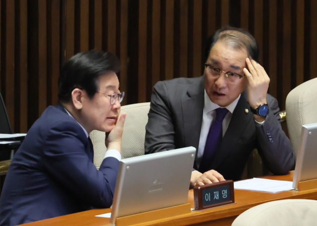 이재명(왼쪽) 더불어민주당 대표가 13일 오후 열린 국회 본회의에서 이성만 의원과 대화하고 있다. 연합뉴스