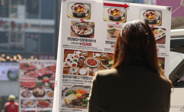 서울 명동의 한 음식점 앞에서 한 시민이 가격표를 보고 있다. 연합뉴스