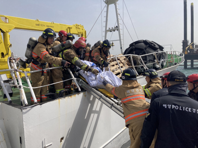 21일 오후 울산 앞바다에서 화재가 난 러시아 어선이 울산항 용연부두로 예인된 가운데 수색 작업에 나선 소방대원들이 시신 1구를 내리고 있다. 울산=장지승기자