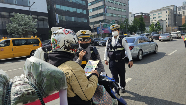 강남경찰서 관계자가 우회전 일시 정지 규칙을 위반한 이륜차 운전자를 계도하고 있다. 정유민 기자