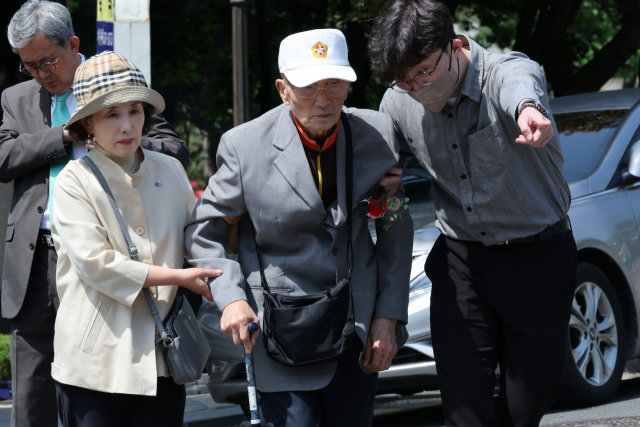 한국전쟁 때 북한에 잡혔다가 탈북한 국군 포로 김성태(사진 가운데)씨가 8일 오전 북한을 상대로 한 손해배상 소송에서 승소 후 법정을 나서고 있다. 연합뉴스