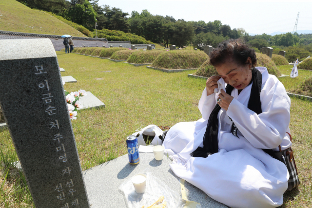 광주 북구 국립 5·18 민주묘지에서 유족이 가족 열사의 묘소 앞에서 눈물을 훔치고 있다. 연합뉴스