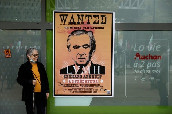 파리에서 한 여성이 베르나르 아르노 LVMH 회장의 초상화가 그려진 가짜 수배 포스터 옆에 서 있다. 로이터=연합뉴스