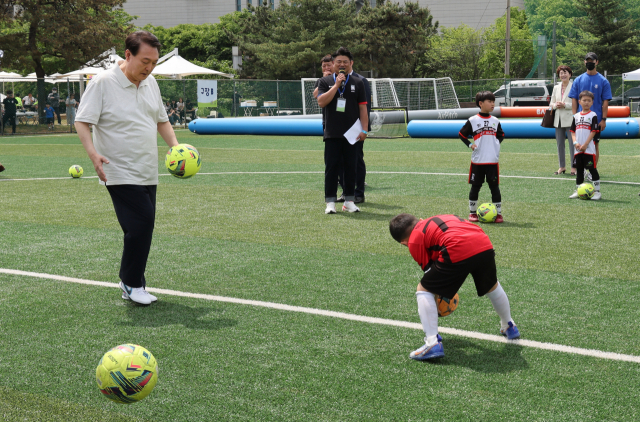 윤석열 대통령이 14일 서울 용산어린이정원 축구장에서 열린 2023 전국 유소년 축구대회에 참가한 어린이들과 공 다루기 대결을 하고 있다. / 연합뉴스