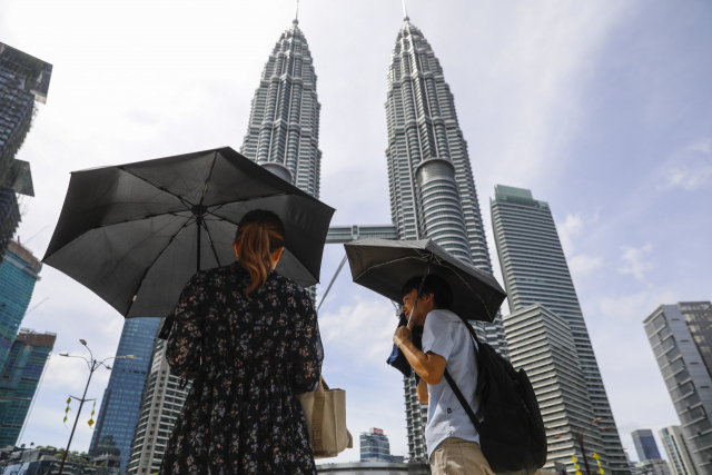 말레이시아 쿠알라룸프에서 한 남녀가 지난달 27일 양산을 쓰고 걸어가고 있다. EPA연합뉴스