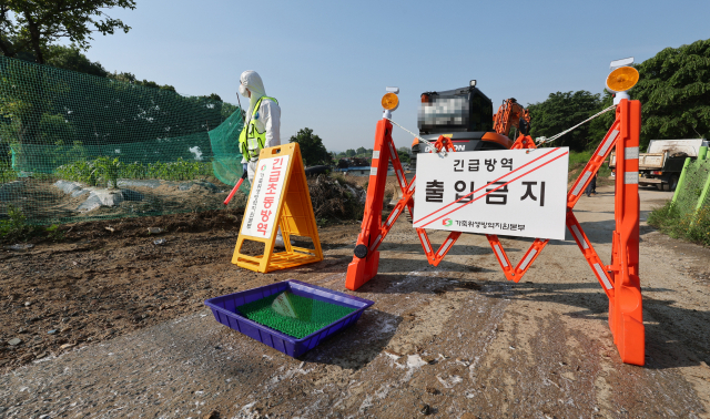 구제역이 발생한 11일 오전 충북 청주시 청원구 북이면의 한 한우농장에서 방역본부 직원이 출입 통제 안내판을 설치하고 있다. 연합뉴스