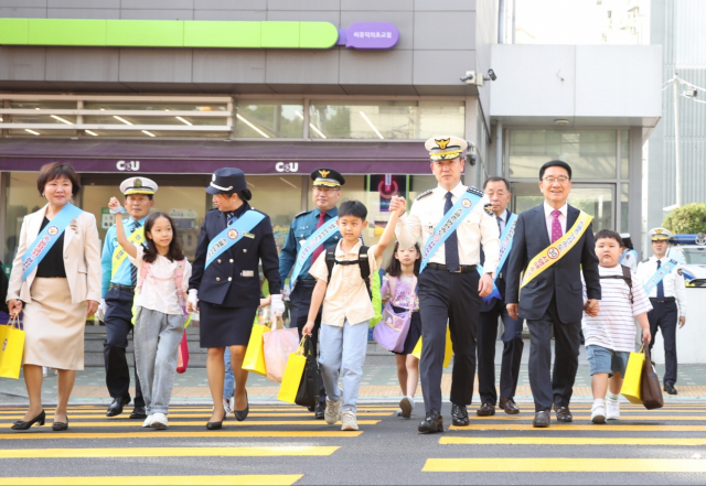 윤희근 경찰청장(오른쪽 다섯 번째)이 17일 오전 서울 구로구 덕의초등학교 인근에서 아이의 손을 잡고 노란색 횡단보도를 건너고 있다.사진제공=경찰청