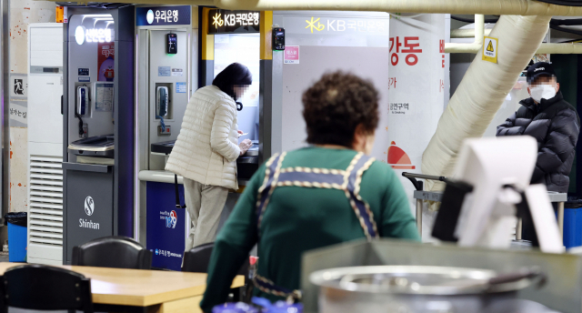 2월 16일 시민들이 서울 시내의 한 시장 내 식당가 앞에 설치된 은행 현금인출기(ATM)를 이용하고 있다. 사진 제공=연합뉴