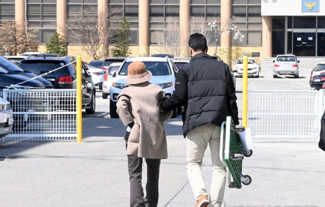 차량 급발진 의심 사고로 12살 손자를 잃고, 교통사고처리 특례법상 치사 혐의로 입건된 60대 할머니 최씨가 지난 3월 20일 첫 경찰조사를 마치고 아들의 부축을 받으며 경찰서를 떠나고 있다. 연합뉴스 캡처