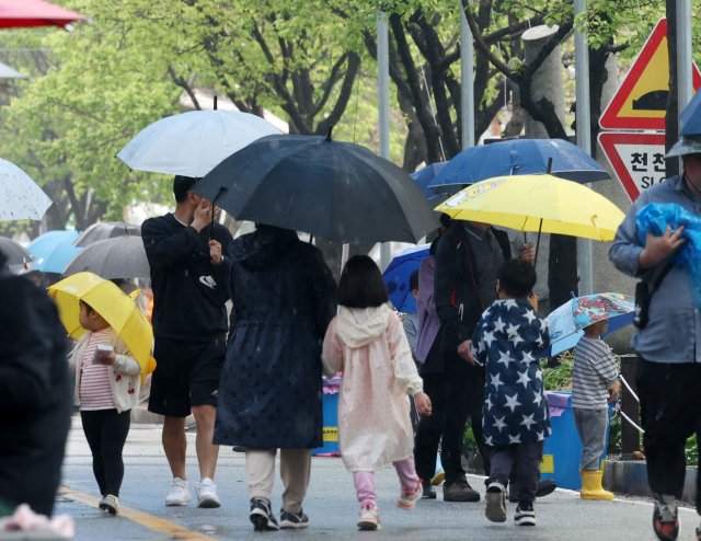 어린이날인 5일 강원 양구군 서천 레포츠공원에서 열린 '2023 양구 곰취축제'에서 우산과 우의 차림의 가족 단위 탐방객들이 궂은 날씨에도 휴일을 즐기고 있다. 연합뉴스