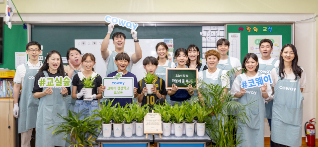 1일 서울 노원구 서울당현초등학교에서 코웨이 임직원과 초등학생들이 '청정학교 교실숲 제4호' 조성 기념 단체 사진을 찍고 있다. 사진 제공=코웨이