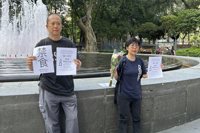 중국의 톈안먼 사태 34주년을 하루 앞둔 3일 톈안 운동가 관춘퐁(왼쪽)과 루카이가 기념행사의 일환으로 홍콩 빅토리아 공원 입구에서 단식이라는 단어가 적힌 종이와 하루 정도 단식할 계획을 자세히 들고 있다. 두 사람은 경찰에 의해 곧 끌려갔다. AP연합