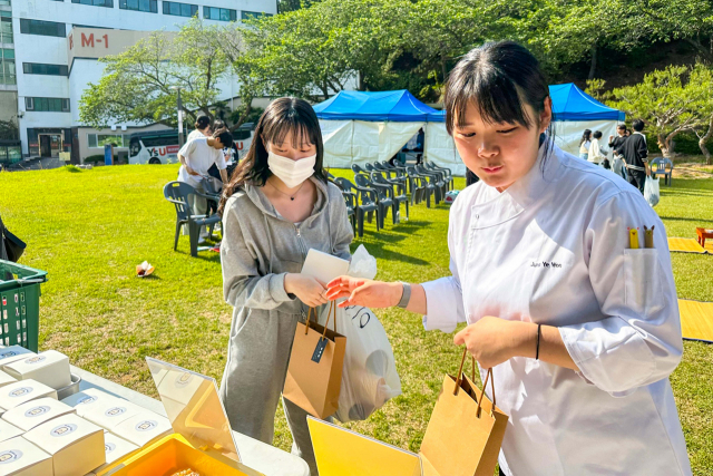 영산대학교 K-Food조리전공이 해운대캠퍼스에서 열린 부산 해운대구의 전통 성년례 행사에서 학생들에게 수제 오란다를 전달하고 있다./사진제공=영산대