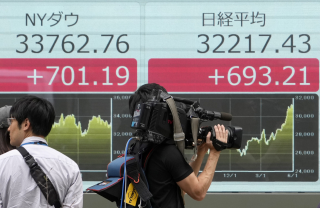 5일 닛케이225 등 각국 주가지수가 표시된 일본 도쿄의 한 전광판 앞에 카메라맨 등 방송 취재진이 서 있다. 일본 경제 부활에 대한 기대감이 높아지고 해외투자 자금이 몰려들면서 닛케이225 지수는 이날 3만 2217.43으로 마감, 1990년 7월 이후 처음으로 3만 2000 선을 넘었다. EPA연합뉴스