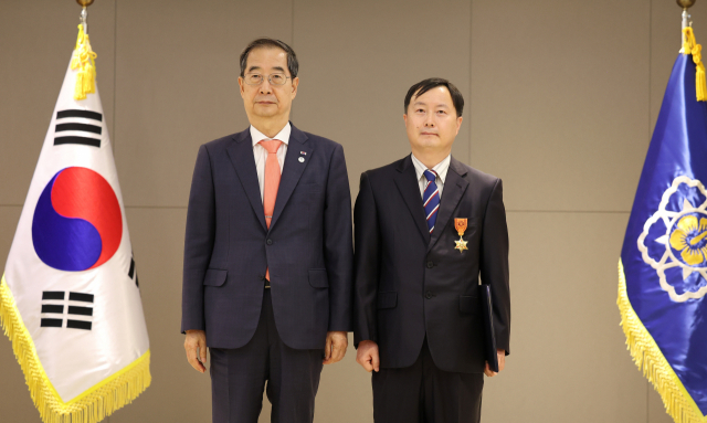 한덕수(왼쪽) 국무총리가 8일 오후 정부세종청사에서 열린 적극 행정 유공자 포상 수여식에서 최은철 농림축산식품부 농업사무관에게 녹조 근정훈장을 수여한 뒤 기념 촬영을 하고 있다. 연합뉴스