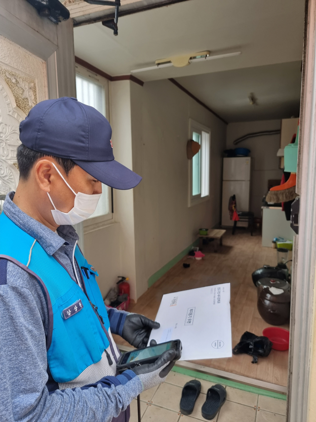 강상원 집배원이 지난달 26일 부산 영도구의 단독 주택에서 복지등기를 배달하고 있다.