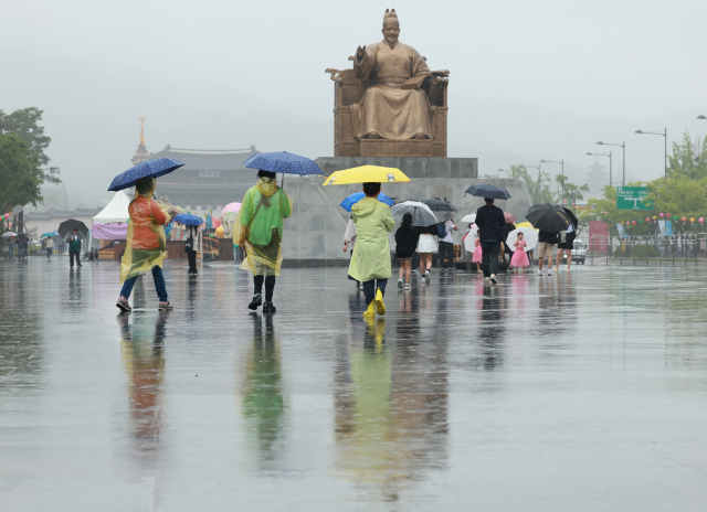 28일 서울 세종대로 광장에서 우산을 쓰고 우비를 입은 시민이 오가고 있다. 연합뉴스