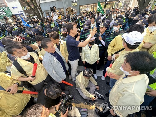 (대구=연합뉴스) 윤관식 기자 = 17일 오전 대구 중구 반월당역 인근에서 퀴어문화축제 측 무대차량 진입을 위해 교통 정리에 나선 경찰관들과 이를 막으려는 대구시 공무원들이 대치한 가운데 대구시 한 간부 공무원이 부상을 주장하며 바닥에 앉아 있다. 2023.6.17 psik@yna.co.kr