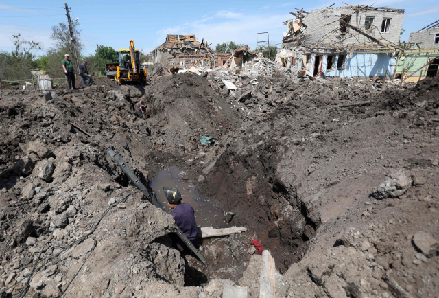 우크라이나 동부 도네츠크주 크라마토르스크 공무원들이 14일(현지시간) 러시아의 미사일 공격으로 생긴 구덩이에서 수습 작업을 하고 있다. 이날 파블로 키릴렌코 도네츠크 주지사는 러시아군이 간밤에 민간인 주택 등을 공습해 3명이 숨졌다고 밝혔다. 연합뉴스