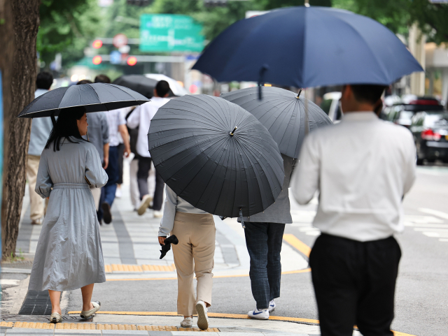 비가 내린 20일 오후 서울 중구 서울시청 인근에서 시민들이 우산을 쓰고 걷고 있다. 연합뉴스