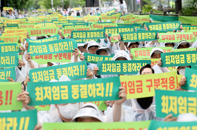 21일 오후 서울 국회의사당역 인근에서 열린 ‘최저임금 동결 촉구 결의대회’에서 소상공인연합회원들이 관련 손피켓을 들어보이고 있다. 연합뉴스