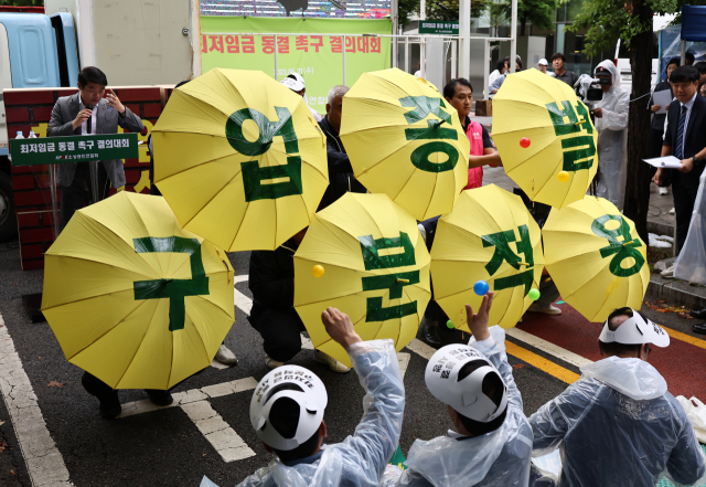 21일 오후 서울 국회의사당역 인근에서 열린 최저임금 동결 촉구 결의대회에서 소상공인연합회원들이 관련 퍼포먼스를 하고 있다. 연합뉴스