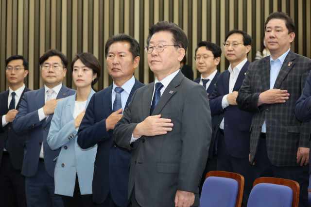 이재명 더불어민주당 대표와 의원들이 21일 오전 국회에서 열린 의원총회에서 국기에 경례하고 있다. 연합뉴스