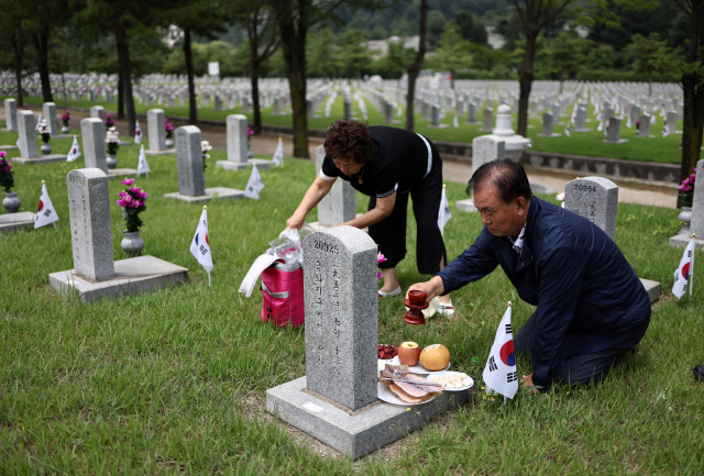 6·25 전쟁 73주년을 사흘 앞둔 22일 국립서울현충원에서 1953년 금화지구에서 전사한 육군 일등중사 서원융의 유족들이 묘를 찾아 참배하고 있다. 연합뉴스