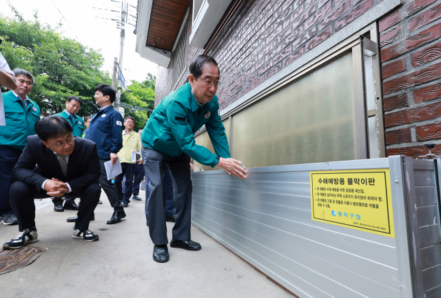 한덕수 국무총리가 23일 서울 동작구 도림천 저지대 주택가를 찾아 호우 시 작동하는 수해예방용 물막이판을 살피고 있다. 연합뉴스