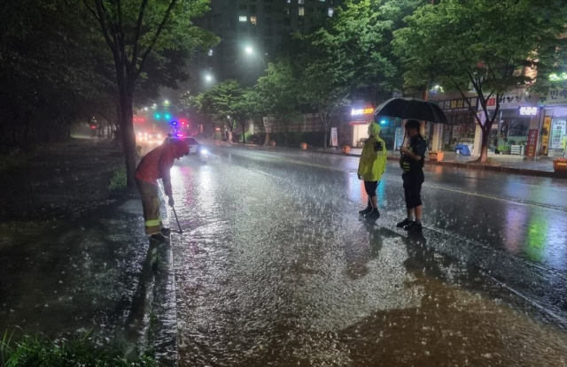 호우경보가 발효된 27일 오후 광주 서구 금호2동 주민센터 앞 교차로에서 소방당국이 배수 작업을 하는 모습. 연합뉴스