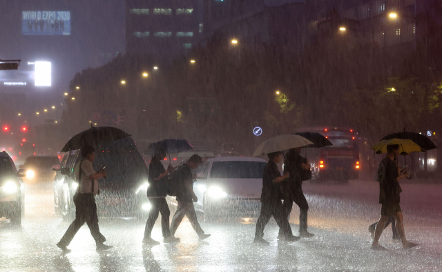 서울 전역에 호우주의보가 발효된 지난 4일 오후 서울 광화문 광장에서 시민들이 우산을 쓴 채 이동하고 있다. 연합뉴스
