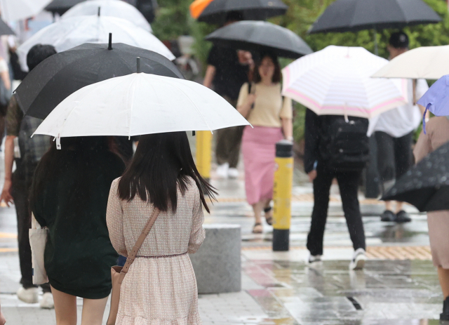 11일 오전 서울 강남구 강남역 인근에 갑자기 소나기가 내리자 시민들이 우산을 쓰고 걸어가고 있다. 연합뉴스