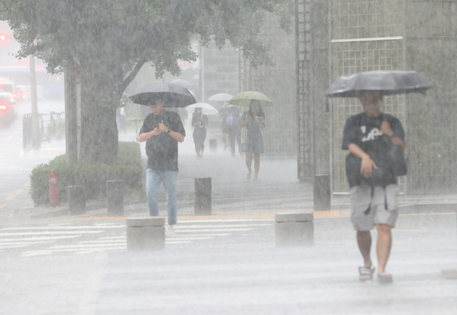 11일 오전 서울 강남구 강남역 인근에 갑자기 소나기가 내리자 시민들이 우산을 쓰고 걸어가고 있다. 연합뉴스