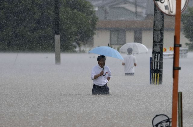 일본 후쿠오카현 구루메시에서 10일 집중호우로 물에 잠긴 주택가 도로를 시민들이 지나가고 있다. 로이터 연합뉴스