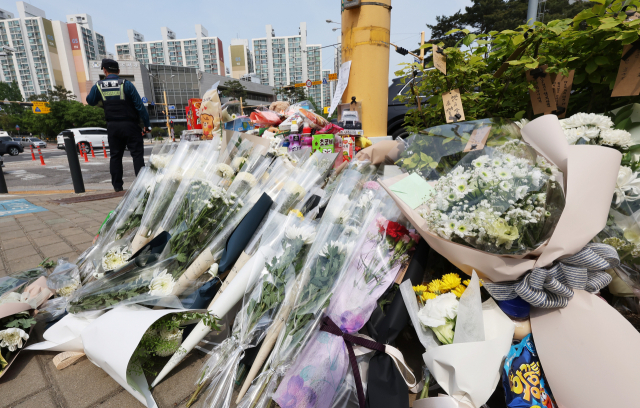 지난 5월11일 오후 경기도 수원시의 한 사거리에 전날 어린이보호구역(스쿨존)에서 시내버스에 치여 숨진 초등학생을 추모하는 시민들이 놓고 간 꽃과 장난감 등이 쌓여 있다. 연합뉴스