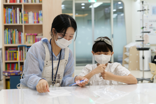 조규리(오른쪽) 어린이가 꿈틀꽃씨쉼터에서 대학생 나누미 봉사자와 함께 색칠 놀이를 하고 있다. 사진 제공=서울대병원
