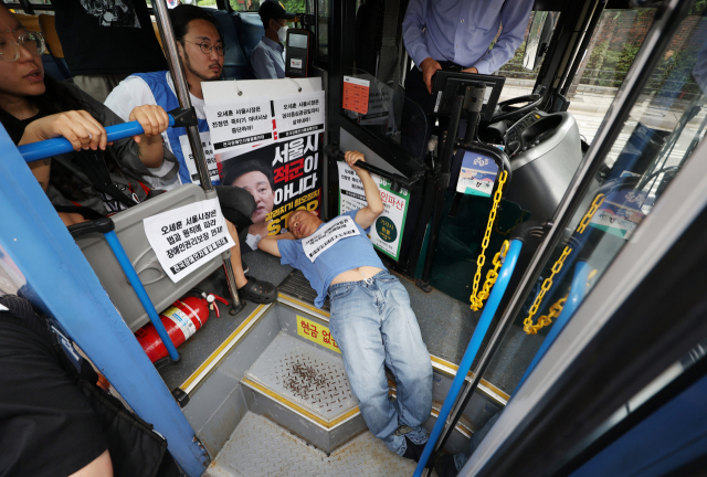 전국장애인차별철폐연대 활동가가 17일 서울 한 버스 정류장에서 버스 탑승 시위를 벌이고 있다. 연합뉴스