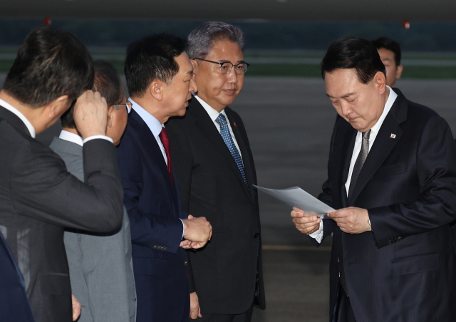 윤석열 대통령이 17일 경기 성남시 서울공항으로 귀국하며 김기현 국민의힘 대표가 준비한 수해 관련 자료를 살펴보고 있다, / 연합뉴스