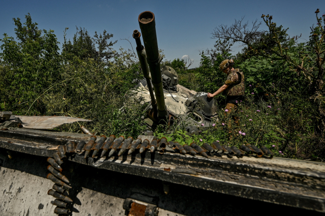 21일(현지 시간) 우크라이나 노보다리카 마을에서 한 군인이 파괴된 러시아군 장비를 검사하고 있다. 로이터연합뉴스