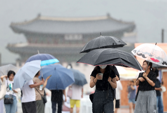 서울 전역에 호우주의보가 발효 중인 지난 23일 오전 서울 광화문광장에서 시민들이 우산을 쓴 채 걸어가고 있다. 연합뉴스