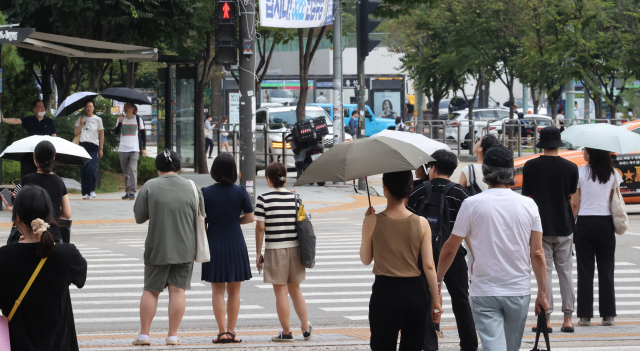 전국에 폭염특보가 내려진 3일 서울 용산구 용산역 인근에서 시민들이 양산을 쓴 채 이동중이다. 연합뉴스