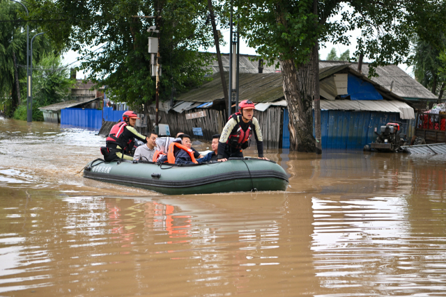 소방관들이 5일 중국 헤이룽장성 하얼빈의 옌서우현에서 홍수로 발이 묶인 주민들을 이송하고 있다. 신화연합