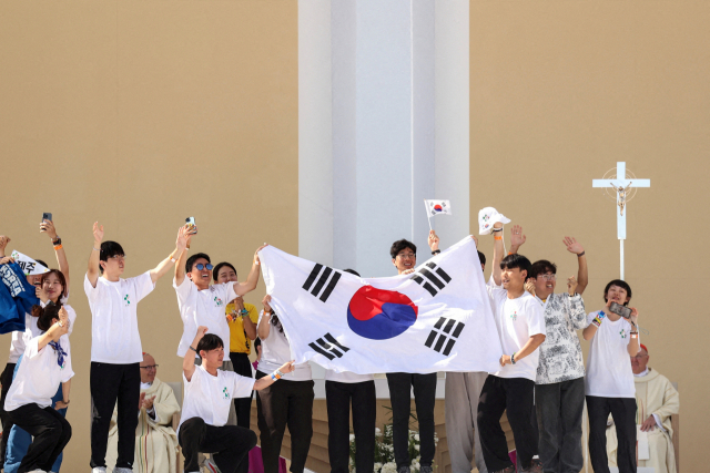 6일(현지시간) 포르투갈 리스본 테조공원에서 열린 세계청년대회 폐막일 미사에서 프란치스코(오른쪽 뒤) 교황이 서울을 2027년 차기 대회 개최지로 발표하자 한국 청년들이 태극기를 흔들며 기뻐하고 있다. 로이터연합뉴스