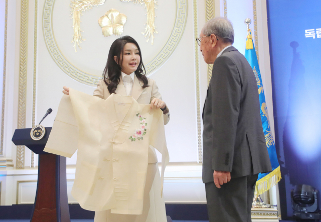 김건희 여사가 9일 청와대 영빈관에서 열린 독립유공자 및 유족 초청 오찬에서 김영관 애국지사에게 무궁화 자수가 새겨진 한산모시 적삼을 선물하고 있다. / 연합뉴스