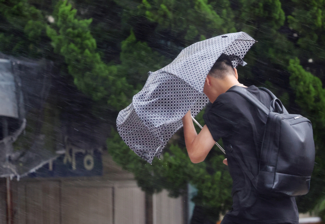 제6호 태풍 '카눈'이 남해안에 상륙을 앞두고 있는 10일 오전 부산 해운대구에서 시민들이 강풍을 피해 힘겹게 출근길에 오르고 있다. 연합뉴스