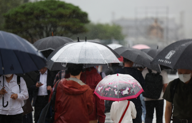 전국적으로 태풍 ‘카눈’의 영향으로 많은 비가 내린 10일 서울 광화문네거리에 퇴근길 시민들이 우산을 쓰고 걸어가고 있다. 연합뉴스