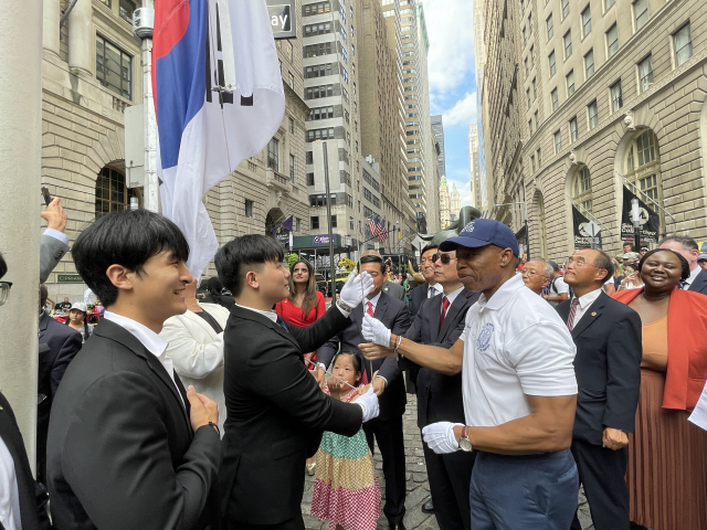 14일(현지 시간) 미국 뉴욕 월스트리트의 ‘돌진하는 황소상’ 앞에서 에릭 애덤스(앞줄 오른쪽) 뉴욕시장이 태극기를 게양하고 있다. 뉴욕=연합뉴스