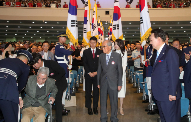 윤석열 대통령이 15일 78주년 광복절 경축식이 열린 서울 서대문구 이화여대 대강당에서 경축식에 입장 중인 오성규(왼쪽), 김영관 애국지사(가운데)가 입장하는 모습을 지켜보고 있다. / 연합뉴스